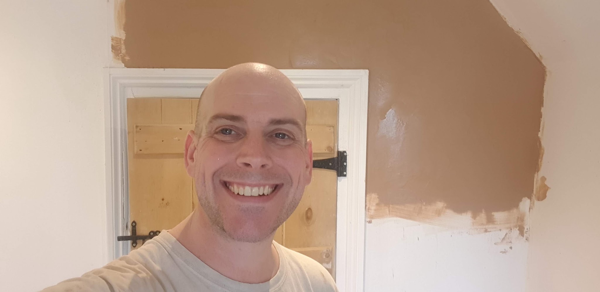 Smiling man in front of a half-finished wall of fresh plaster